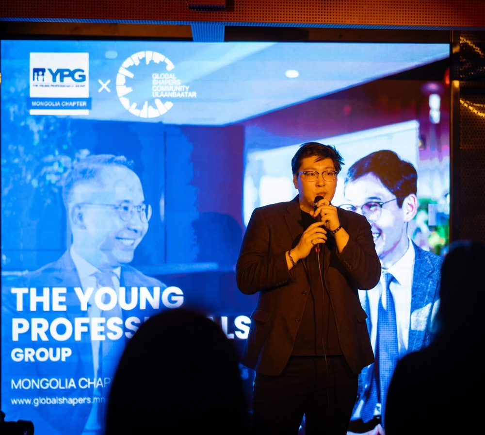 Anar speaking on stage at a YPG Mongolia event